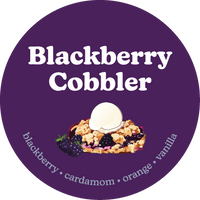 Purple circular label with "Blackberry Cobbler" text, illustrated cobbler with ice cream, and blackberries on dark purple bac