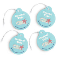 Four turquoise round car charms with white string, each featuring "Coastal Tide" text, a starfish, shell illustration, and sc