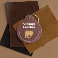 Four leather swatches in brown, tan, and black tones with a round mauve charm labeled "Vintage Leather" featuring a gold leaf