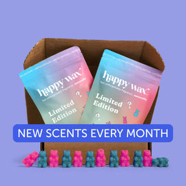 Brown cardboard box containing two gradient-colored Happy Wax Limited Edition candle packages with pink and blue wax melts ar