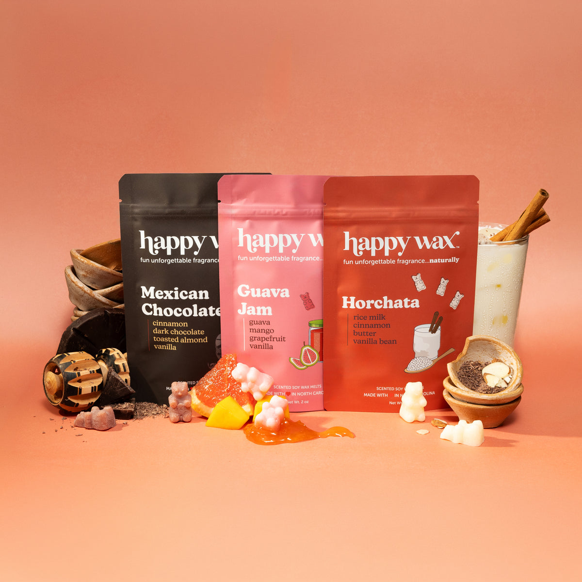 Three 'happy wax' wax melt packages on a peach-colored background with decorative items.