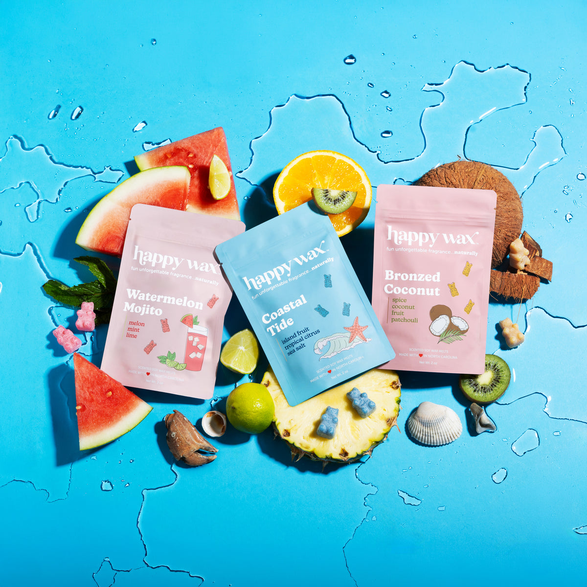 Three Happy Wax melt pouches on a blue background with fruit slices and shells.