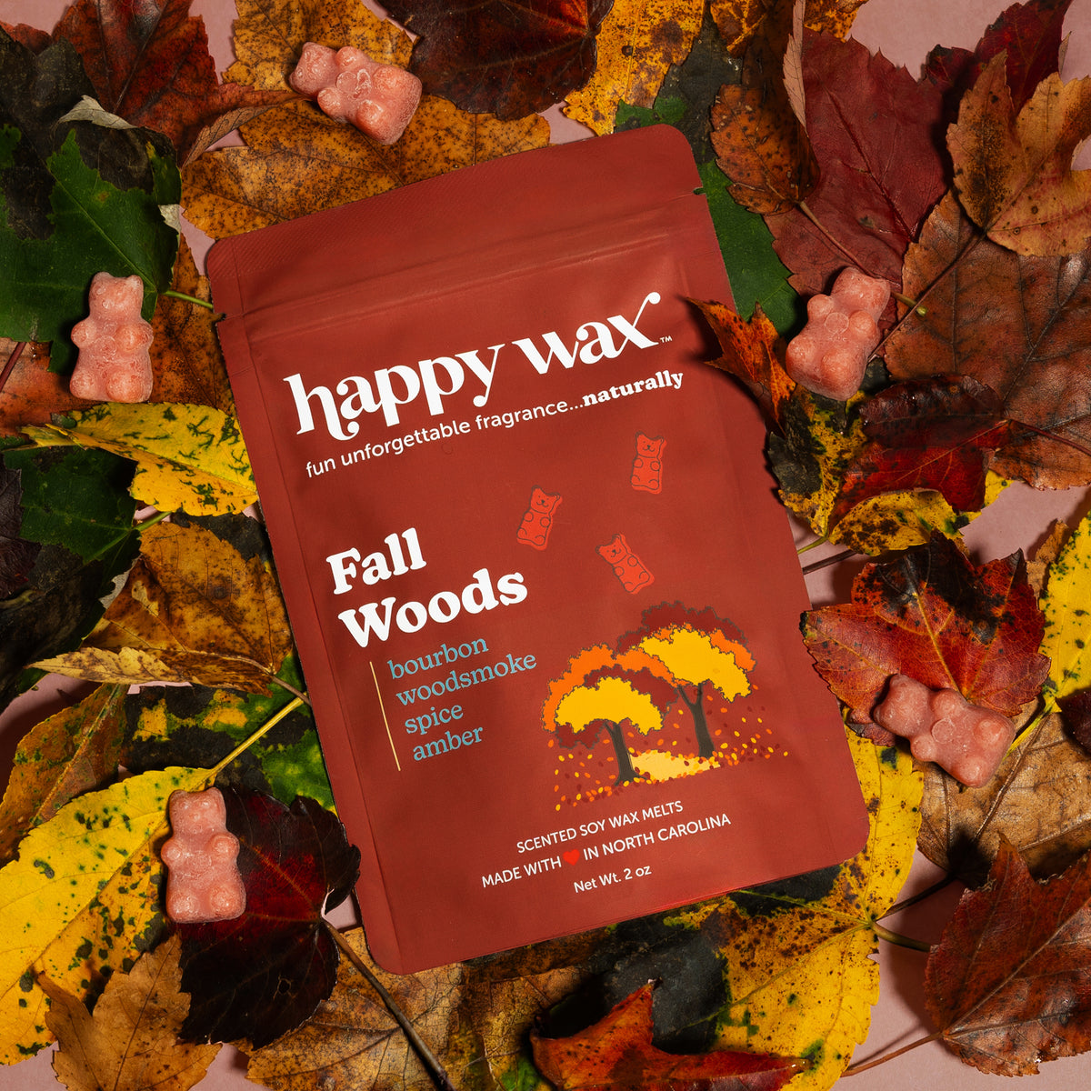 Red Happy Wax Fall Woods wax melt package surrounded by dried branches and autumn leaves.