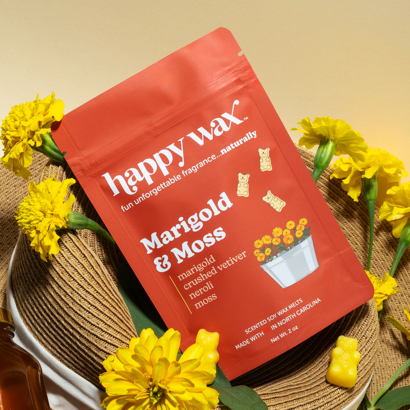 Happy Wax Marigold & Moss Pouch on a wicker hat with yellow marigolds and yellow wax bears on muted yellow background