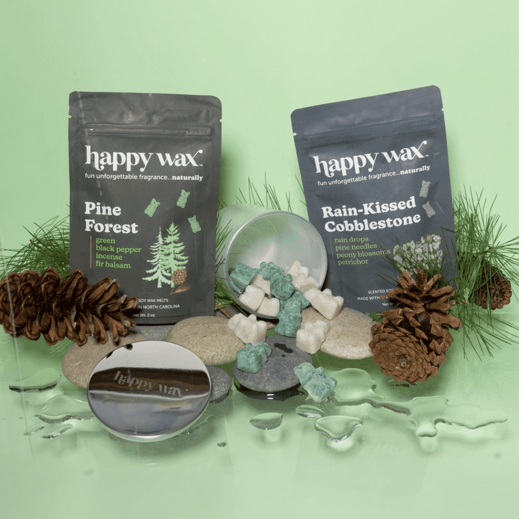 Happy Wax melt pouches and iridescent jar on green background with pine cones and rain