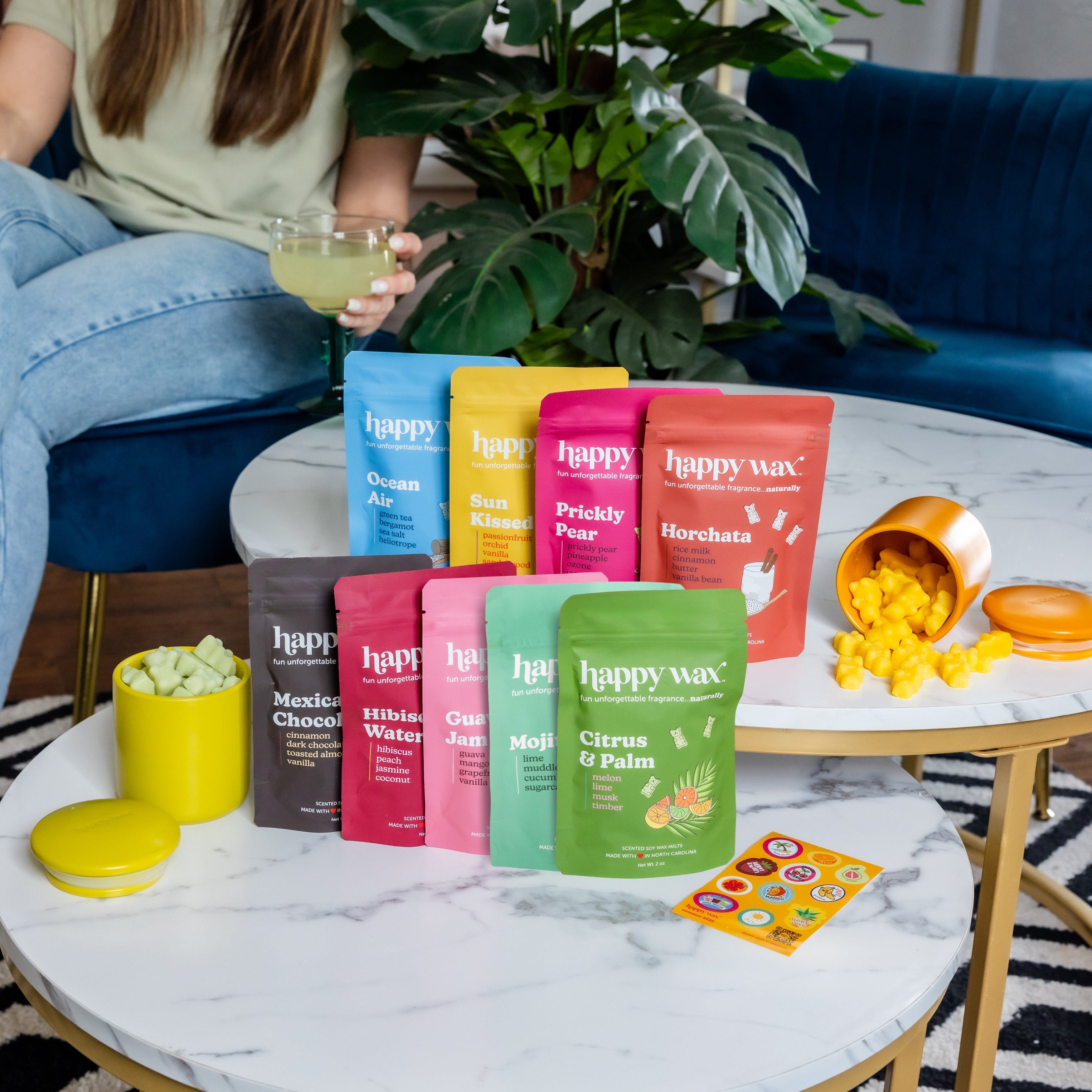 Woman sitting on a couch with Happy Wax summer collection wax melts displayed on a coffee table.