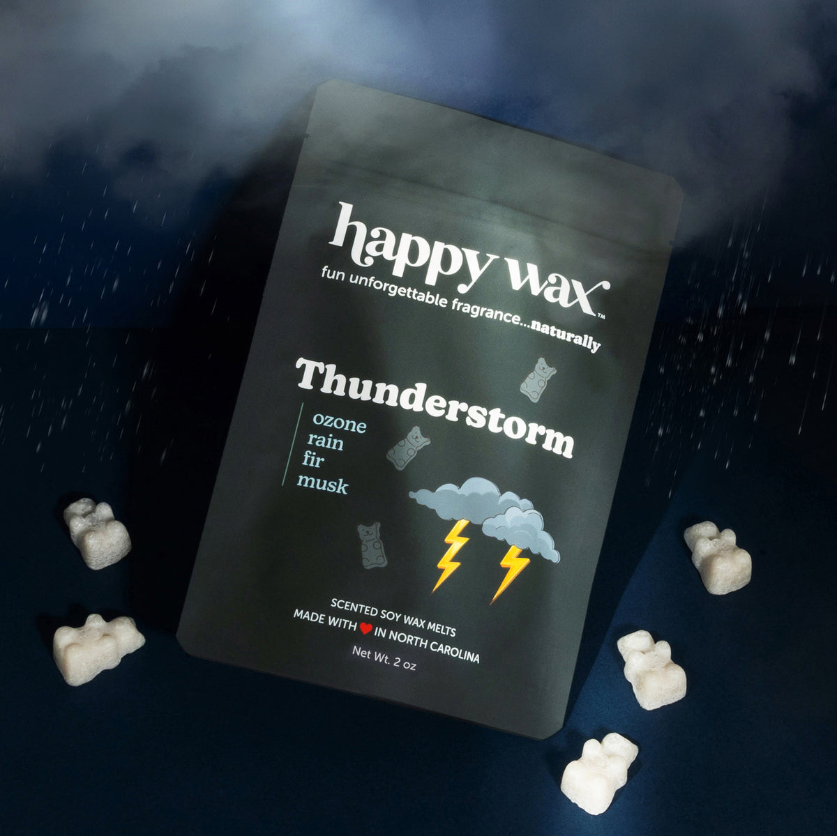 Dark grey pouch of thunderstorm scented soy wax melts with grey wax bears displayed beside it in an stormy setting with rain cloud and raindrops on a navy background