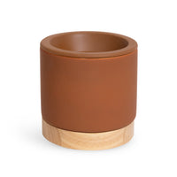 Cylindrical wax warmer with terracotta ceramic top and natural wood base.