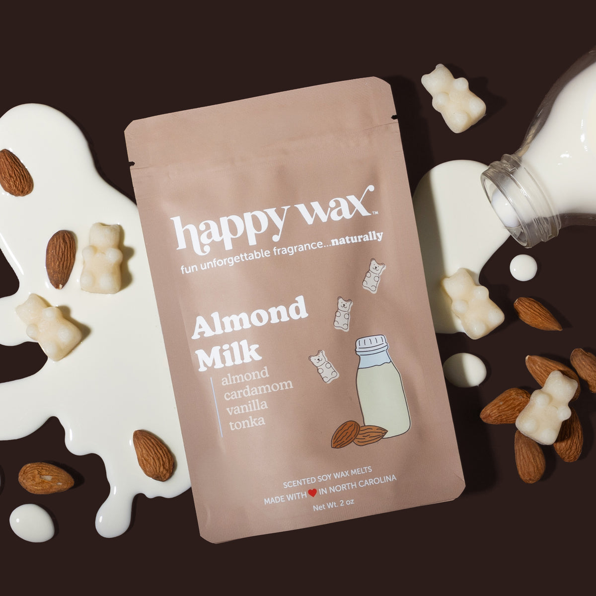 Happy Wax Almond Milk packaging with spilt almond milk, almonds, and wax bears scattered around, on dark brown background
