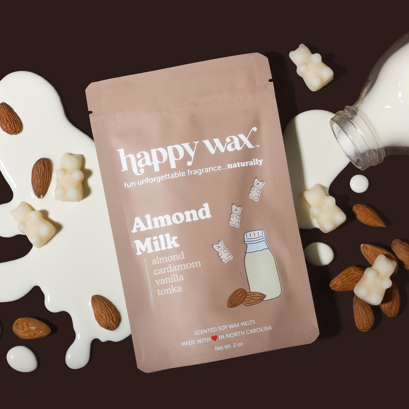 Happy Wax Almond Milk packaging with spilt almond milk, almonds, and wax bears scattered around, on dark brown background