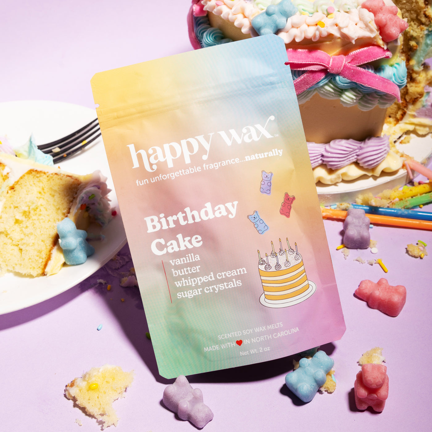Happy Wax Birthday Cake pouch with pastel colored wax bears and cake with pastel piped frosting on light purple background