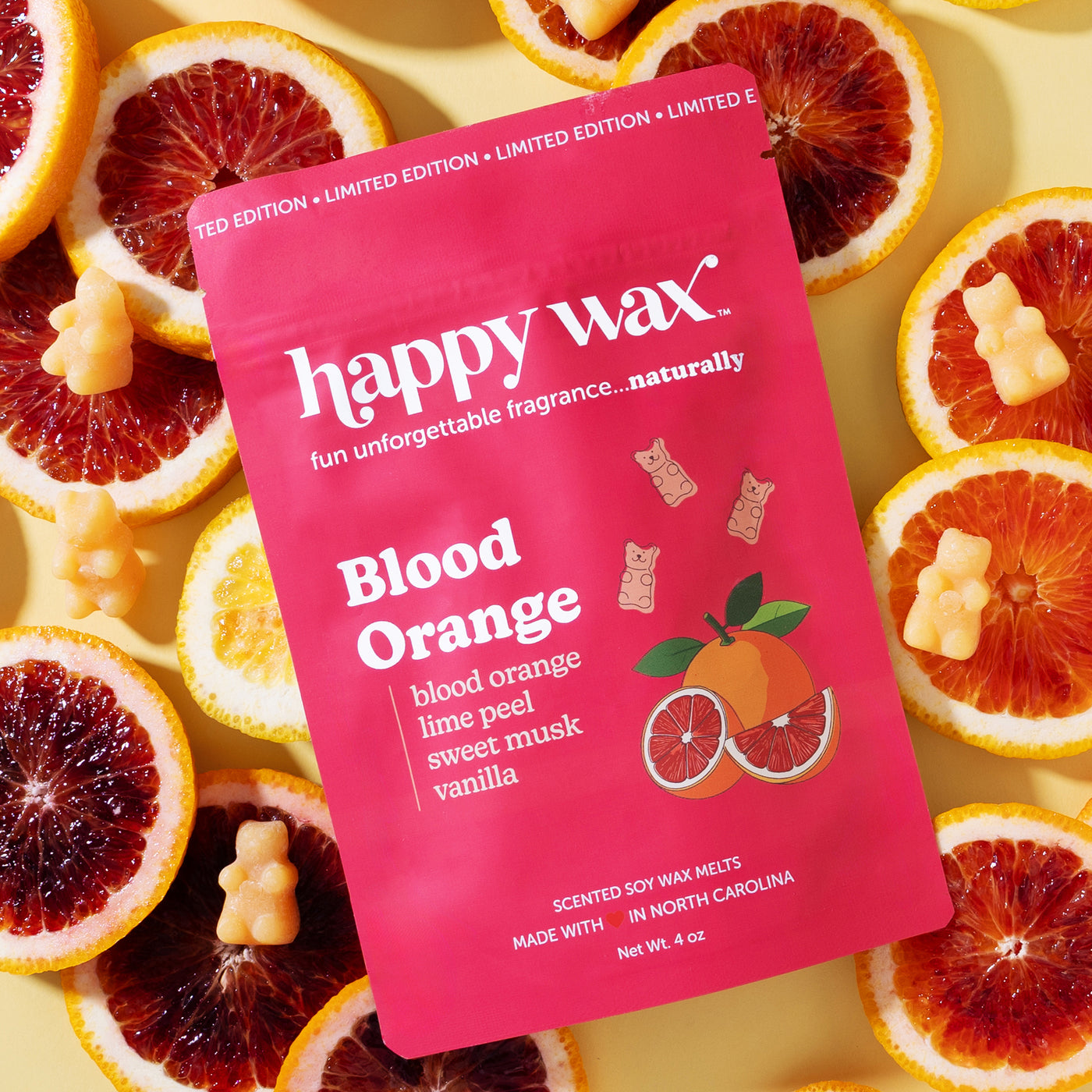 Happy Wax Blood Orange wax melt packaging surrounded by sliced blood oranges on a yellow background