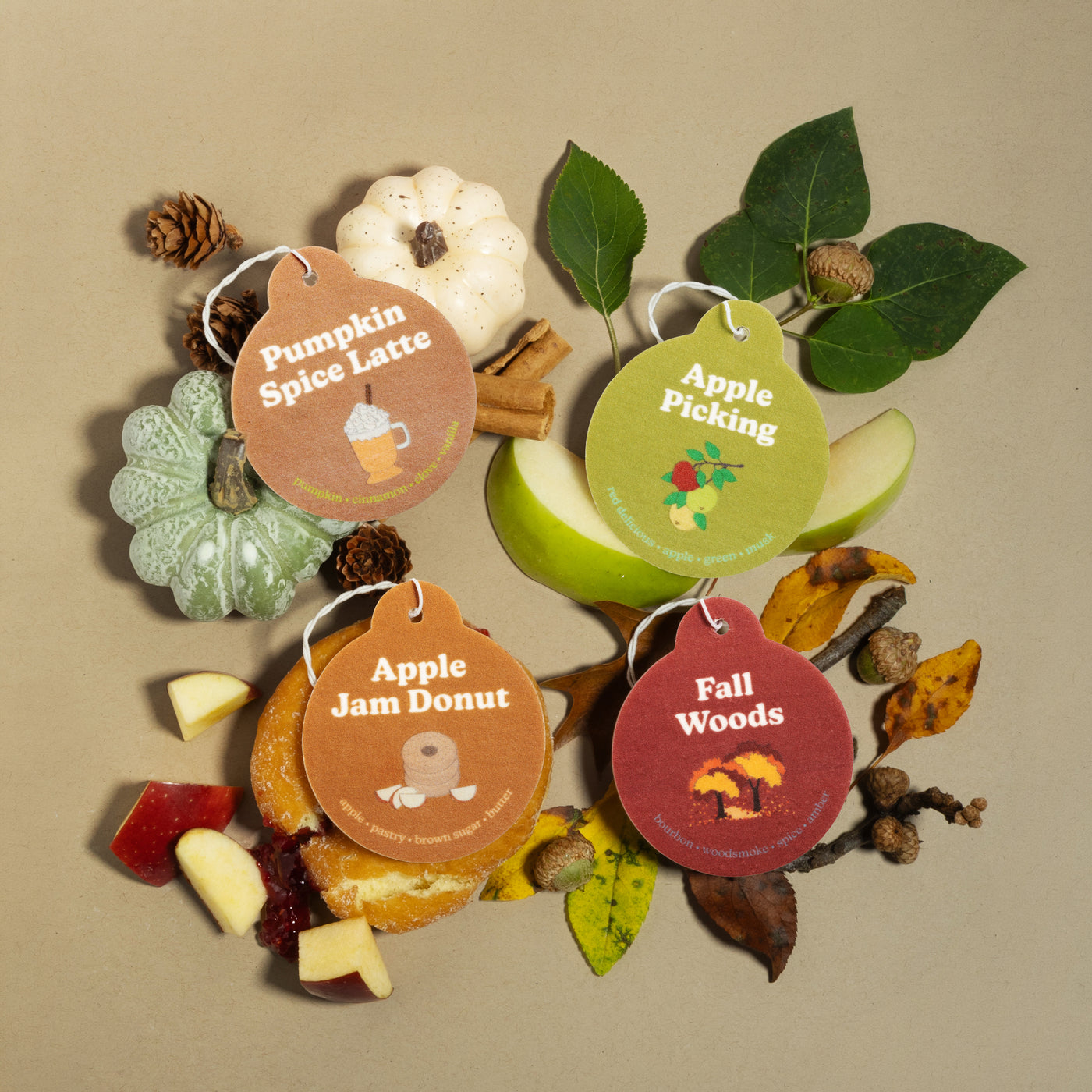 Happy Wax Fall Mix Car Charms including Pumpkin Spice Latte, Fall Woods, Apple Picking and Apple Jam Donut with various ingredient props on tan background.