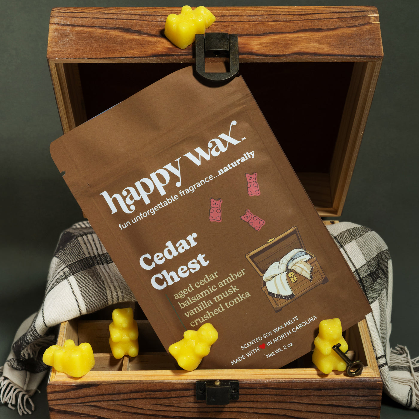 Yellow bear-shaped wax melts in a brown paper package inside an open wooden cedar chest with metal clasp.