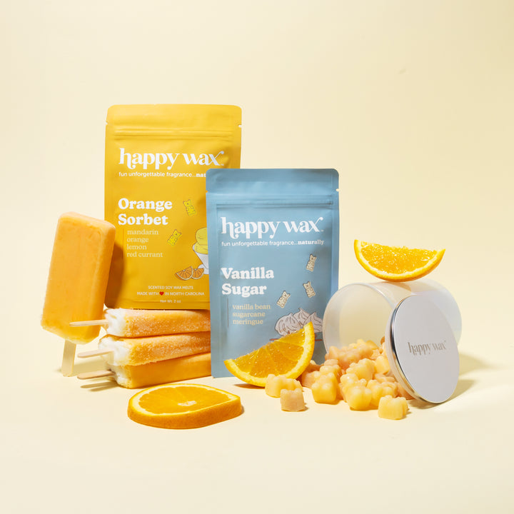 Happy Wax melt pouches and storage jar on cream background with oranges and popsicles