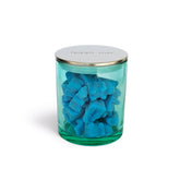 Green jar filled with blue wax melts and a silver lid on a white background