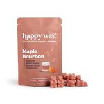Rose-colored wax melt cubes next to a happy wax brand pouch labeled Maple Bourbon with ingredient list and maple leaf illustr
