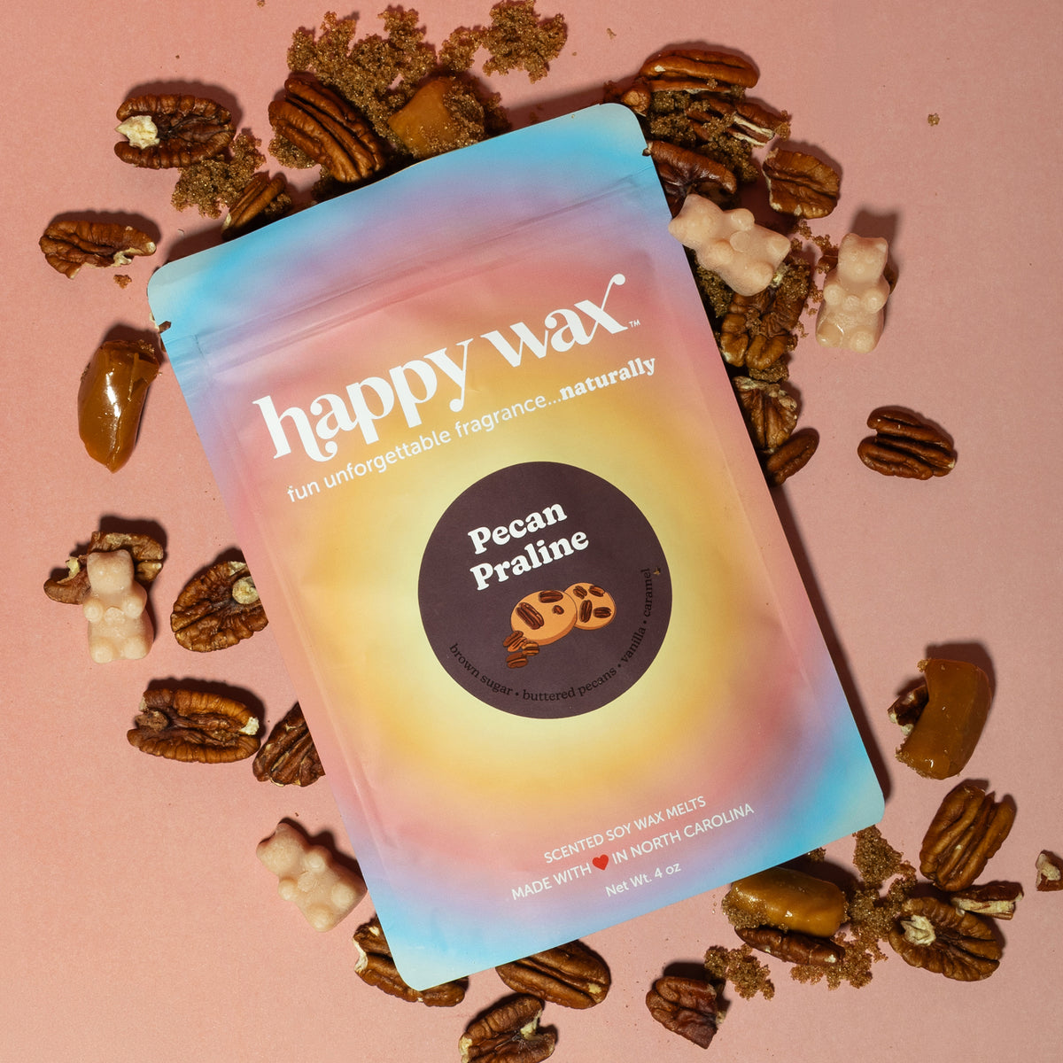 Happy Wax Pecan Praline Pouch with pecans, brown sugar and caramel treats on a pink background