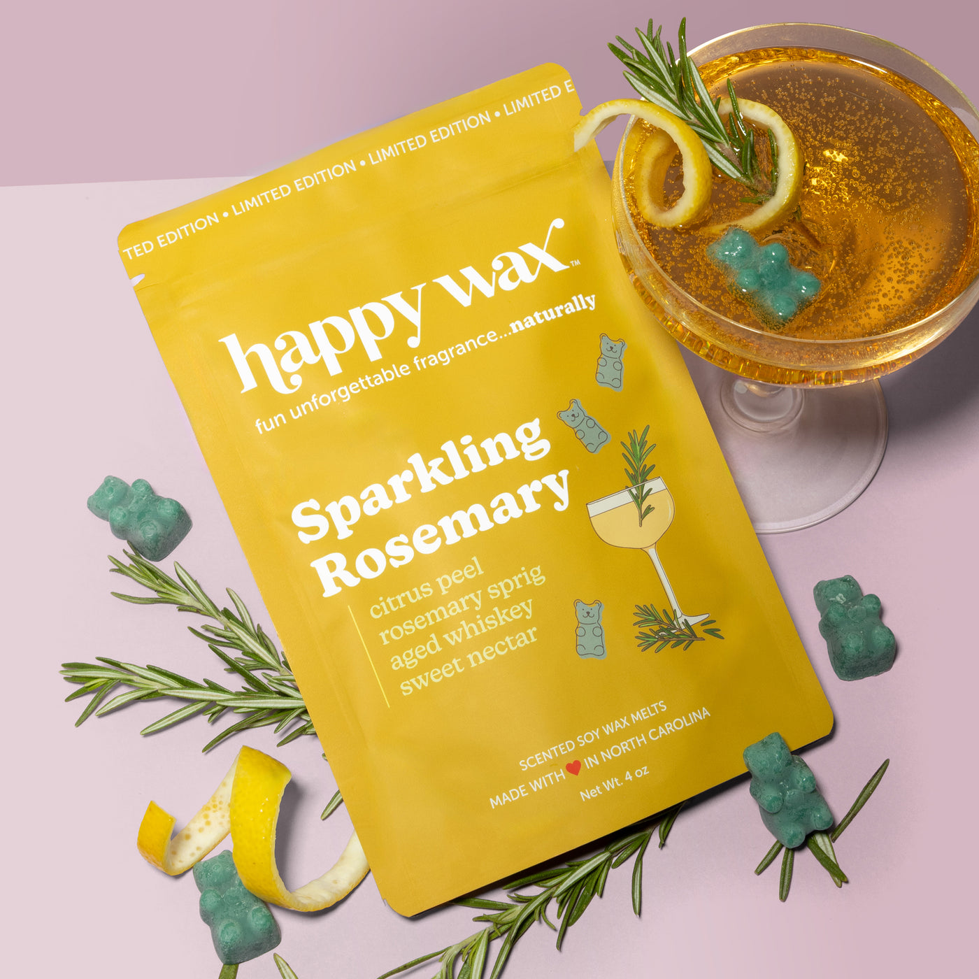 Happy Wax Sparkling Rosemary pouch with sparkling drink, rosemary sprigs, lemon peel, and green wax bears on light pink background
